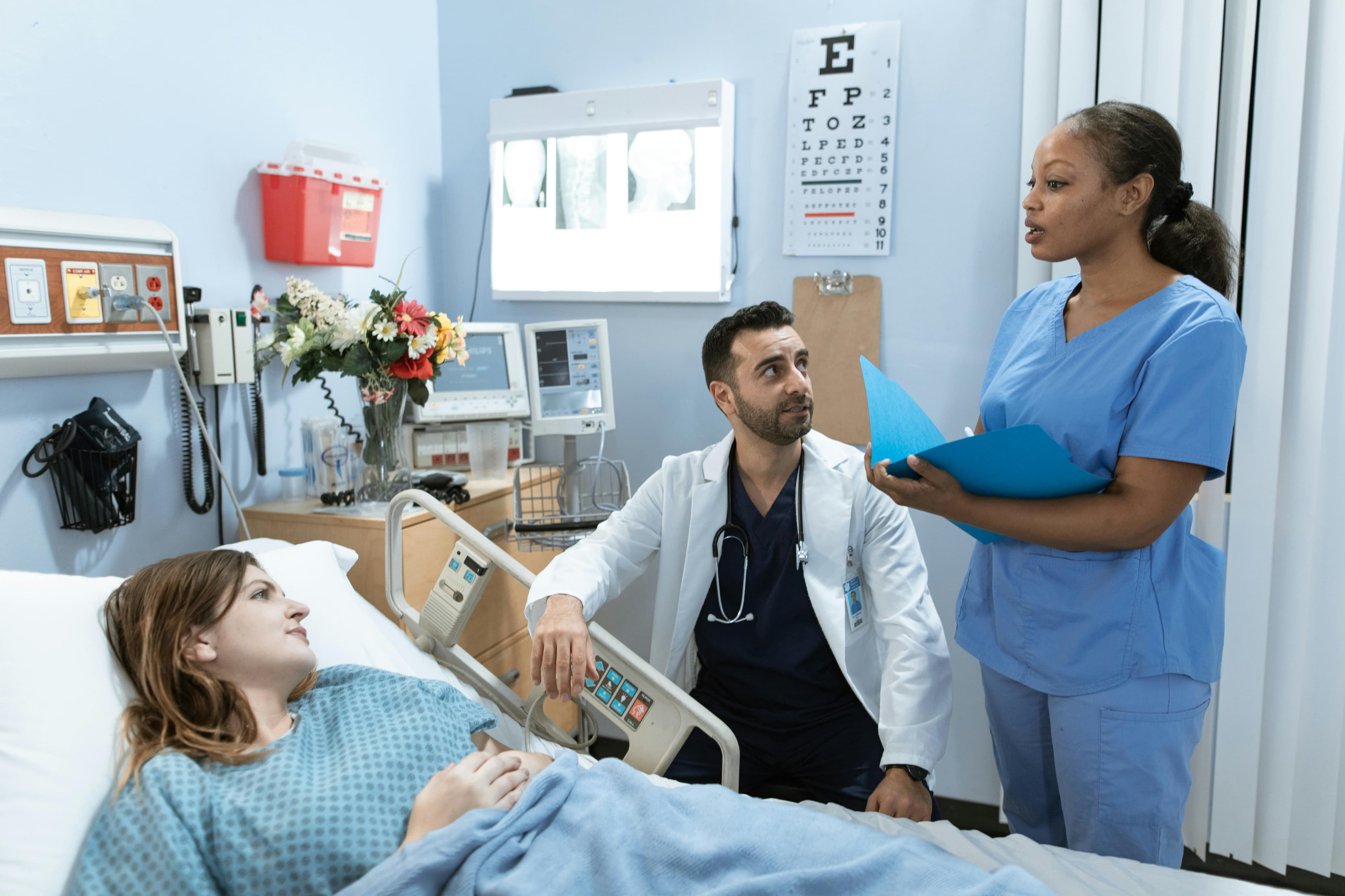 Nurse and physician coordinating bedside care with a patient.